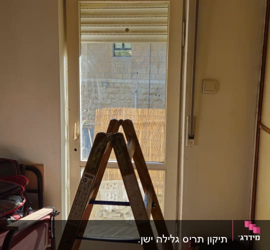 סולם עץ ניצב מול חלון ותריס גלילה במהלך עבודת תיקון